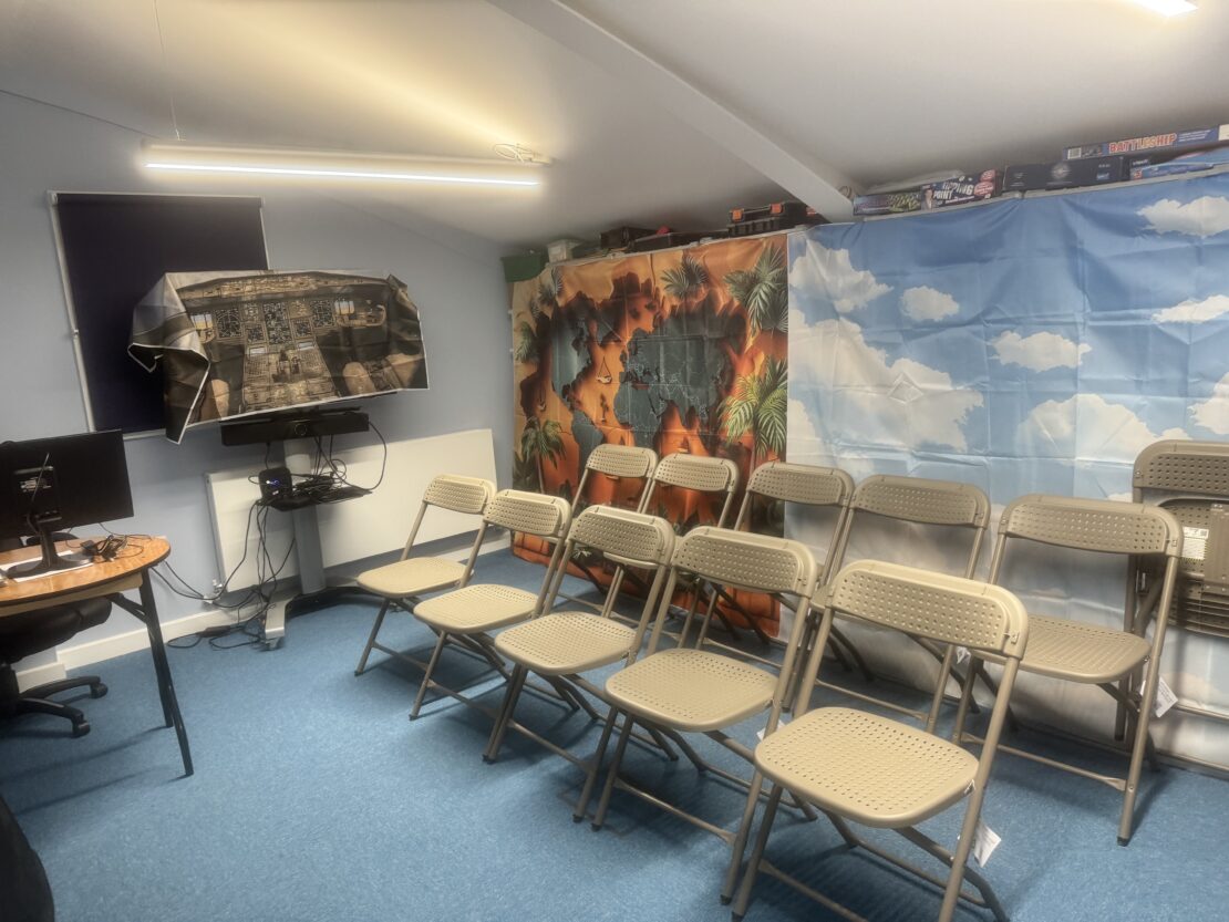 Several chairs lined up in a meeting room. Decorative cloth screens are hung up behind the chairs to create a background.